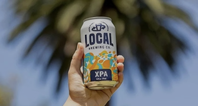 Local Brewing Co. XPA can held up against a palm tree
