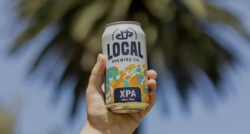 Local Brewing Co. XPA can held up against a palm tree